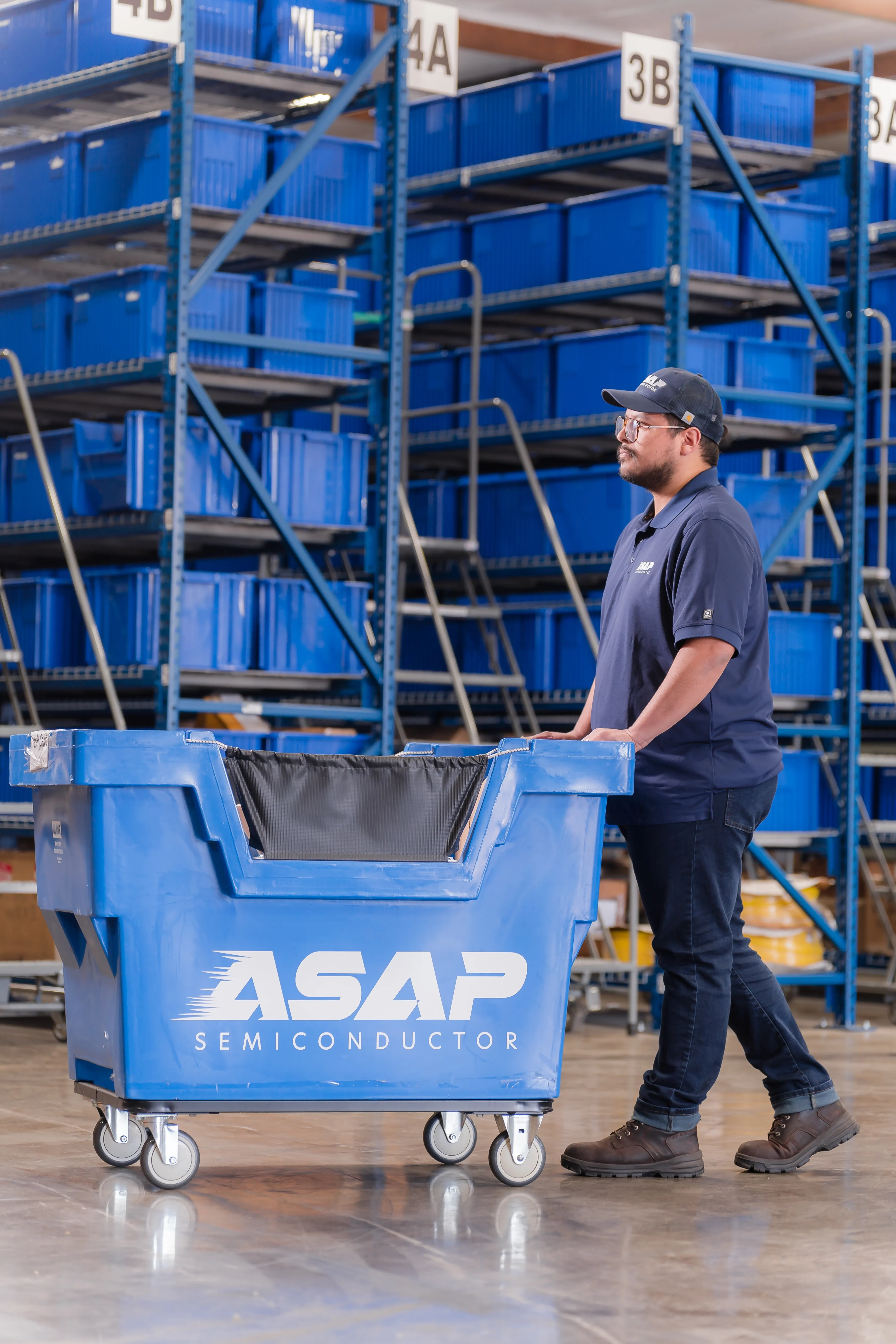 ASAP Components team members handling a packaged part beside a branded parts cart in the warehouse
